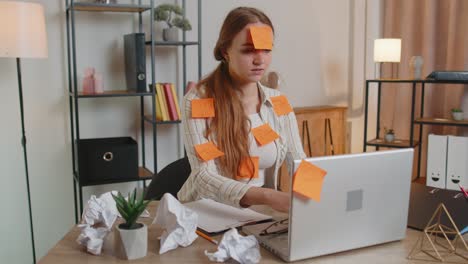 Exhausted-woman-freelancer-with-pasted-stickers-using-laptop-having-concentration-problem-in-office