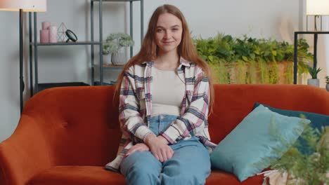 Portrait-of-happy-one-beautiful-teenager-student-girl-smiling,-looking-at-camera-at-home-on-sofa