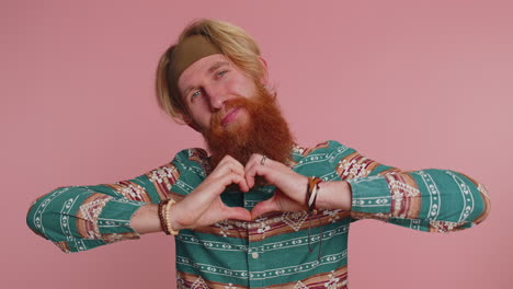 Smiling-redhead-man-makes-heart-gesture-demonstrates-love-sign-expresses-good-feelings-and-sympathy