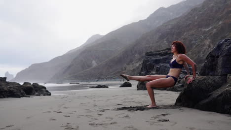 The-ocean-serves-as-a-backdrop-as-a-young,-slender-female-athlete-executes-slow-motion-push-ups-on-a-rock