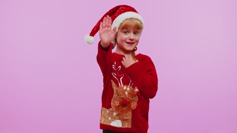 Child-girl-in-Christmas-sweater-waves-hand-in-hello-gesture-welcomes-someone-to-celebrate-New-Year