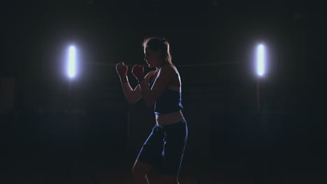 A-strong-athletic,-woman-boxer,-boxing-at-training-on-the-black-background.-Sport-boxing-Concept-with-copy-space.