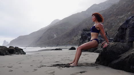 Slow-motion-reveals-a-young-female-athlete's-strength-as-she-engages-in-push-ups-on-a-rock-near-the-ocean
