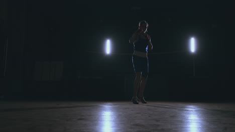 A-beautiful-woman-boxer-trains-in-a-dark-gym-and-works-out-punches-in-slow-motion.-Camera-movement-side-View.-Steadicam-shot