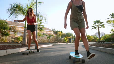 Mit-Skateboards-In-Der-Hand-Navigieren-Sie-In-Zeitlupe-Durch-Die-Parkwege-Der-Insel,-Während-Der-Schein-Des-Sonnenuntergangs-Ihr-Erlebnis-Noch-Verstärkt.-Freude-Und-Einen-Gesunden-Lebensstil