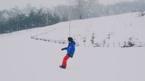 Männlicher-Snowboarder-Fährt-In-Zeitlupe-Auf-Einem-Brett-Im-Schnee-Von-Der-Skipiste