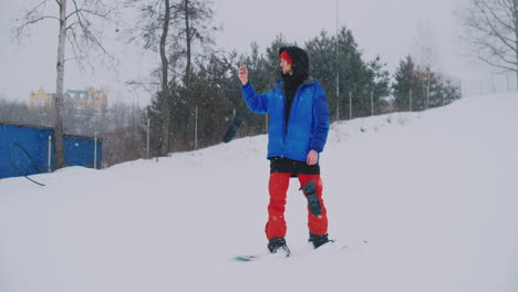 Un-Snowboarder-Masculino-Con-Una-Chaqueta-Azul-Se-Transmite-En-Vivo-Desde-Su-Teléfono-Inteligente-En-La-Estación-De-Esquí