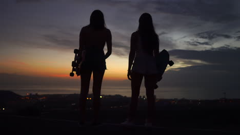 Atop-the-mountain,-friends-pause-from-skateboarding-to-marvel-at-the-scenic-sunset-sky