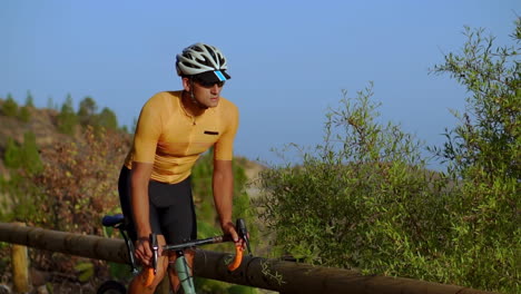 Slow-motion-captures-the-athlete-cycling-atop-a-mountain-serpentine,-gazing-at-the-captivating-island-vista,-exemplifying-the-ideals-of-a-healthy-lifestyle