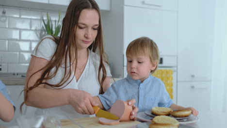 Eine-Junge-Mutter-Hilft-Einem-Kind-Beim-Kochen-Von-Burgern-In-Der-Küche