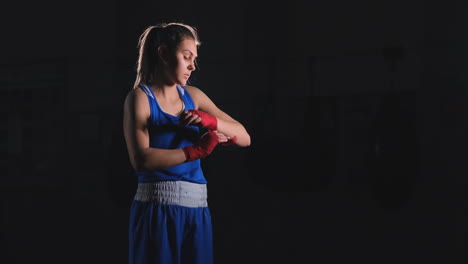 Medium-shot-of-a-beautiful-athletic-female-boxer-pulls-red-bandages-on-the-hands-of-a-female-fighter.-steadicam-shot