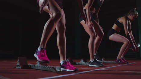 Young-female-runner-athlete-with-smartwatch-ready-to-sprint-at-running-track-starting-line