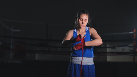 Beautiful-female-boxer-pulls-red-bandages-over-her-arms-in-slow-motion.-steadicam-shot