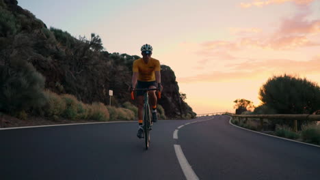 The-athlete-on-a-bike-is-captured-in-slow-motion-riding-a-mountain-serpentine,-enjoying-the-island's-view,-embodying-dedication-to-a-healthy-lifestyle-at-sunset