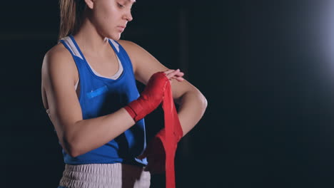 Medium-shot.-Beautiful-female-boxer-wraps-red-bandages-on-hands.-steadicam-shot