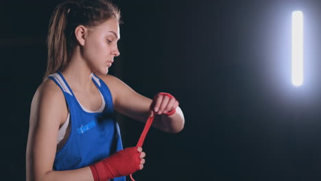 Medium-shot-A-beautiful-female-boxer-pulls-red-bandages-onto-the-wrist-of-a-female-fighter.-steadicam-shot