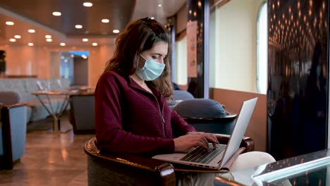 Woman-in-mask-working-on-laptop-on-cruise-ship