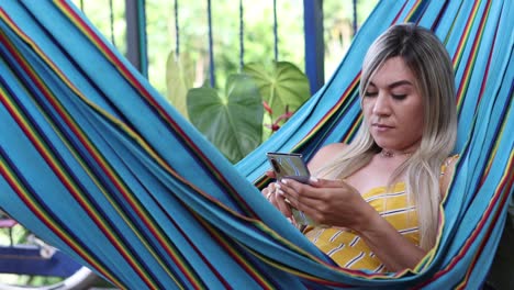 Woman-browsing-smartphone-and-resting-in-hammock
