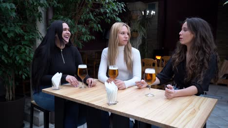 Happy-best-female-friends-laughing-and-drinking-beer-in-bar