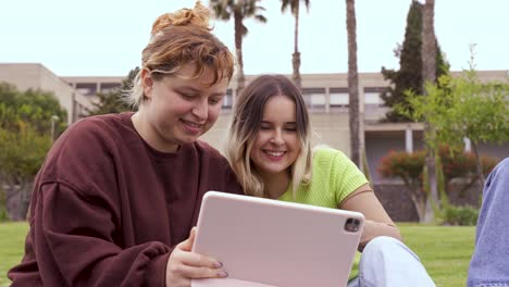 Cheerful-friends-using-tablet-at-university-campus
