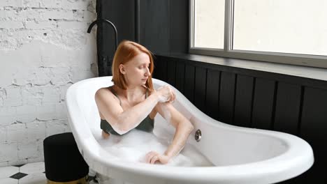 Cheerful-woman-washing-arm-in-bathtub