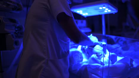 Nurse-touching-fragile-newborn-in-neonatal-incubator