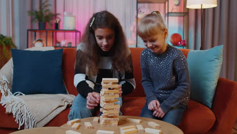 Siblings-children-girls-playing-with-blocks,-board-game,-build-tower-from-wooden-bricks-at-home