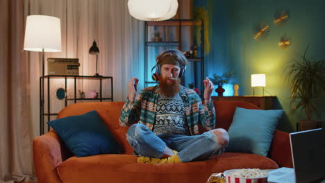 Hippie-redhead-man-at-home-couch-eyes-closed-meditating-with-concentrated-thoughts,-listen-music