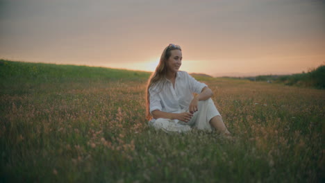 Woman-Sitting-On-A-Meadow-At-Dusk