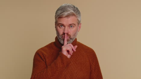 Senior-man-presses-index-finger-to-lips-makes-silence-gesture-sign-do-not-tells-secret-shh-be-quiet