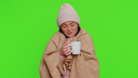 Mujer-Enferma-Usa-Sombrero-Envuelto-En-Tela-Escocesa-Sola-Temblando-De-Frío,-Bebiendo-Té-Caliente,-Tratando-De-Calentarse