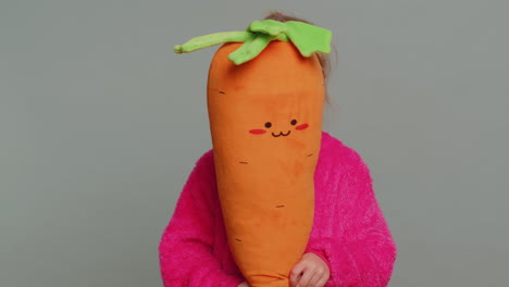 Young-preteen-child-girl-kid-playing-hide-and-seek,-peek-a-boo,-hiding-behind-big-plush-carrot-toy