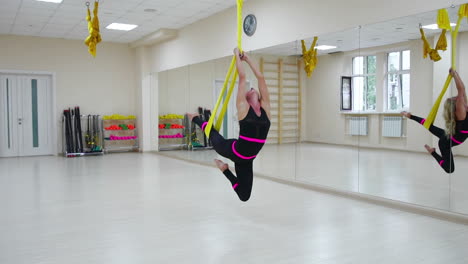 The-concept-of-sports-for-a-healthy-lifestyle.-The-girl-has-been-aerology-of-antigravity-relaxes-and-swings-on-the-canvas-in-a-white-room.-Rotation-on-the-canvas-around-its-axis