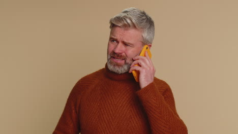 Mature-man-tired-sleepy-freelancer-talking-on-mobile-phone-with-friend-making-online-conversation