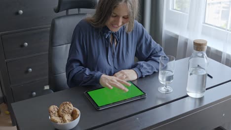 Mujer-Feliz-Usando-El-Dedo-Para-Trabajar-Con-Una-Tableta-En-Su-Escritorio