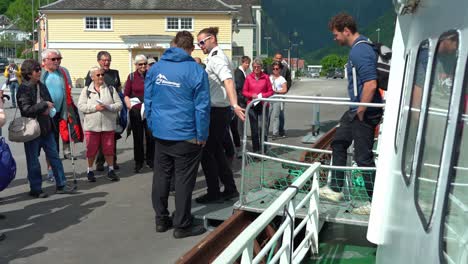 Tourists-disembarking-sightseeing-boat-through-gangway-and-walking-to-Balestrand-quay-in-Norway