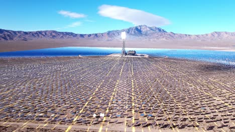 Aerial-of-solar-farm-with-VFX-3D-graphics-in-the-desert,-sun-reflecting-off-tower,-renewable-technology