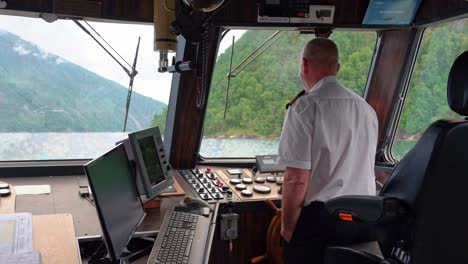 Der-Kapitän-Auf-Dem-Norwegischen-Fjordrundfahrtboot-Lächelt-Und-Lacht-Vom-Steuerhaus-Aus-In-Die-Kamera,-Während-Er-Durch-Den-Sognefjord-Fährt