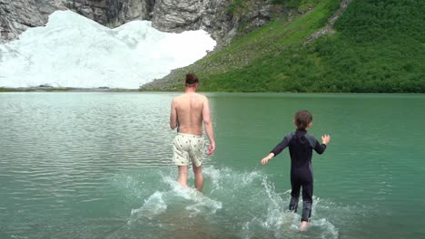 Father-and-son-running-in-to-ice-cold-glacier-water-below-Boyabreen-glacier-in-Fjaerland-Norway---Slow-motion