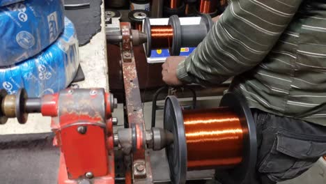 A-Man-Rapidly-rotating-spool-with-copper-wire-getting-reeled-onto-it