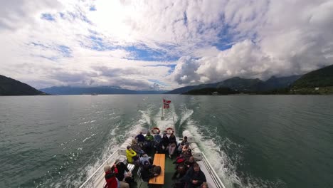 Atemberaubende-Heckansicht-Eines-Touristenbootes,-Das-Durch-Den-Sognefjord-In-Norwegen-Fährt,-Mit-Glücklichen-Menschen-Draußen-Und-Der-Norwegischen-Flagge-Auf-Der-Rückseite-Des-Bootes-–-Weitwinkel