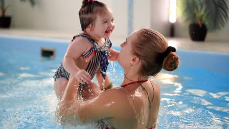 Happy-smiling-toddler-is-jumping-and-diving-under-the-water-in-the-swimming-pool.-An-underwater-shot.-Slowmotion