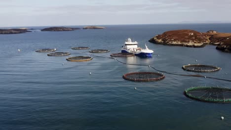 Aufsteigende-Drohnenaufnahme-Einer-Fischfarm-Und-Eines-Brunnenbootes-In-Der-Nähe-Der-Insel-Uist