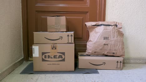 Online-purchases-from-the-retail-companies,-Amazon-and-Ikea,-as-cardboard-boxes-are-seen-in-front-of-a-customer-door