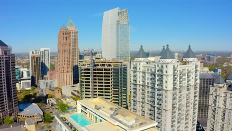Aerial-drone-shot-slowly-rotating-counter-clockwise-around-skyscrapers-near-Piedmont-Park-in-Midtown-near-downtown-Atlanta,-Georgia-on-a-sunny-day-with-blue-skies