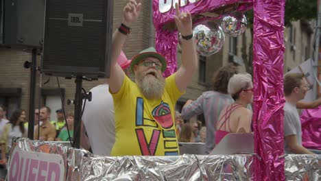 Older-person-with-a-grey-beard-and-Love-written-on-his-t-shirt-dancing-during-the-Antwerp-Pride-Parade-2023-in-Belgium