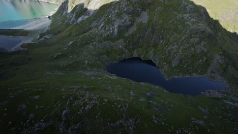 Toma-Cinematográfica-De-Drones-FPV-Estabilizada-Desde-Lofoten-Descendiendo-Una-Montaña-Hacia-Un-Lago-De-Montaña.