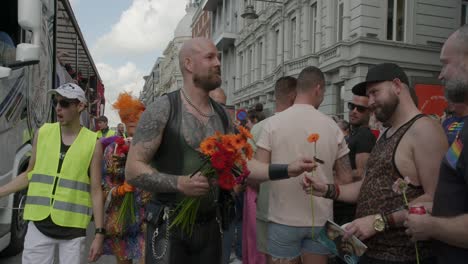 Gay-man-handing-spectators-orange-and-red-flowers-during-the-Antwerp-Pride-Parade-2023-in-Belgium