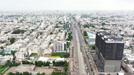 Aerial-cinematic-view-of-ring-road-of-Rajkot-city,-aerial-drone-camera-moving-forward-showing-many-residential-houses-on-both-sides-of-the-road