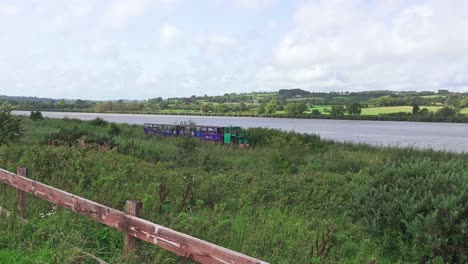 tourist-train-passing-with-river-in-background-at-Waterford-Greenway-Ireland-on-a-warm-summer-day